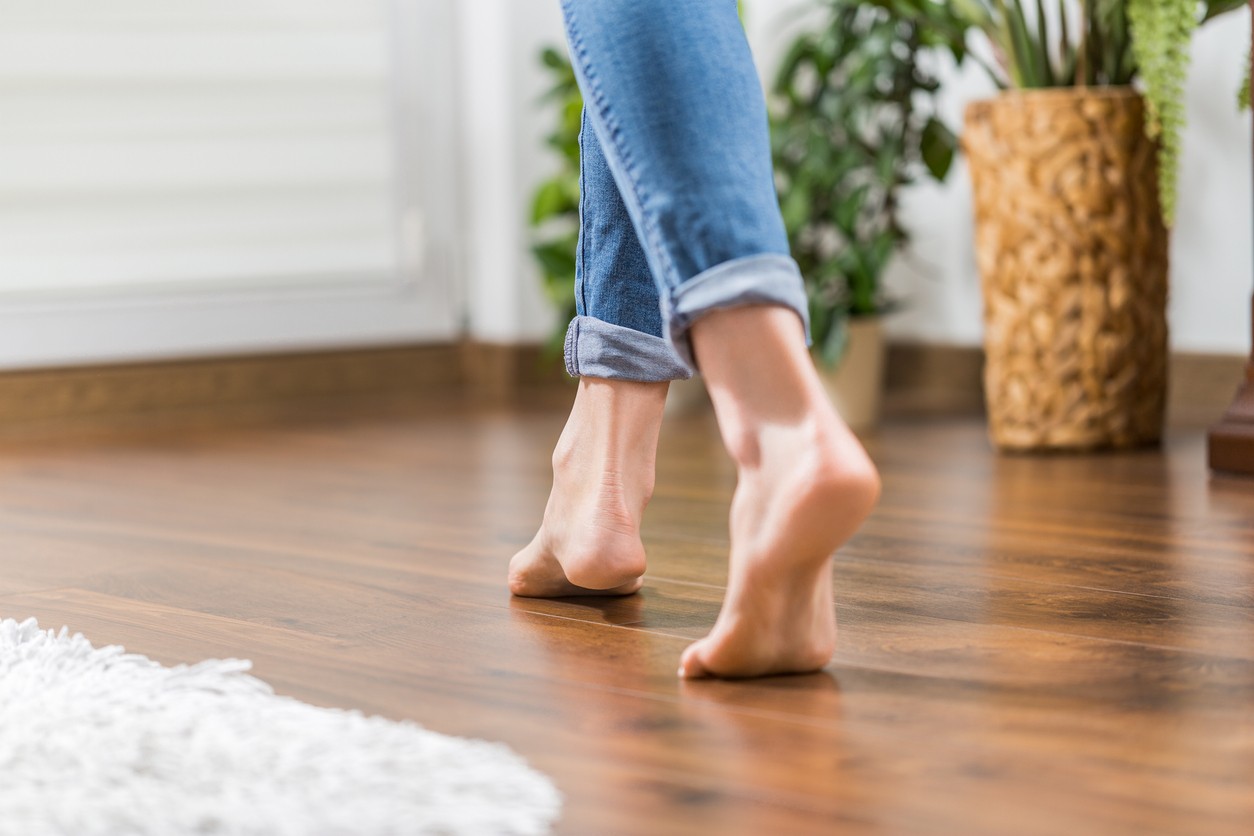Warm floor - the concept of floor heating and wooden panels. Floor heating. Young woman walking in the house on the warm floor. Gently walked the wooden panels.